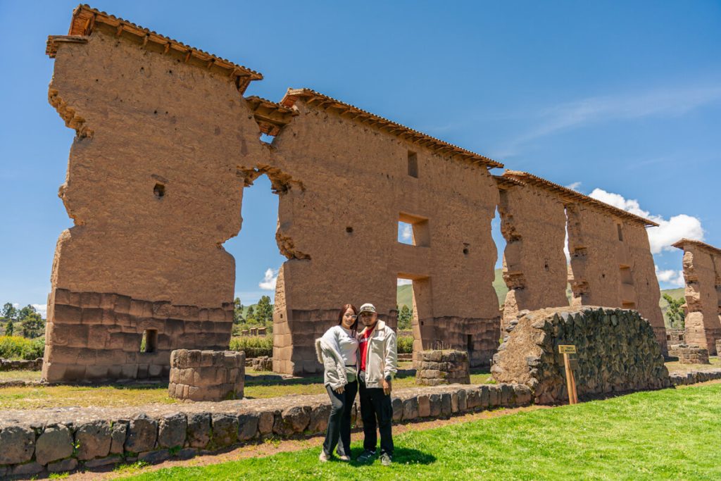Pareja de viajeros felices posando para una foto frente al monumental Templo de Wiracocha en Raqchi - Avalos Tours