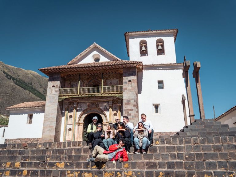 Grupo de viajeros felices posando en las escalinatas de la Iglesia de Andahuaylillas, la Capilla Sixtina de América - Avalos Tours