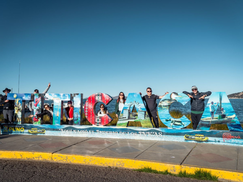 Turistas posando en el colorido letrero de Titicaca a orillas del lago, un lugar turístico clásico en Puno - Avalos Tours