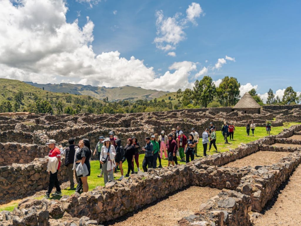 Grupo de turistas en una visita guiada caminando entre las ruinas del sitio arqueológico de Raqchi - Avalos Tours