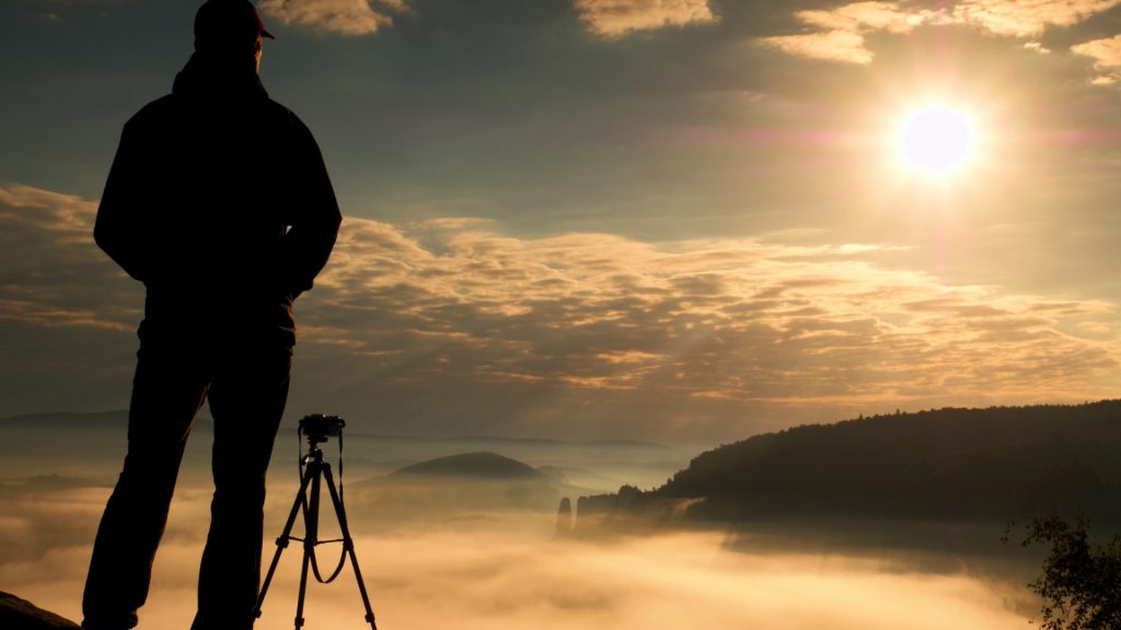 Fotógrafo con trípode capturando el amanecer en los Andes, un ejemplo de la increíble ortografía ruta del sol que se puede lograr - Avalos Tours.